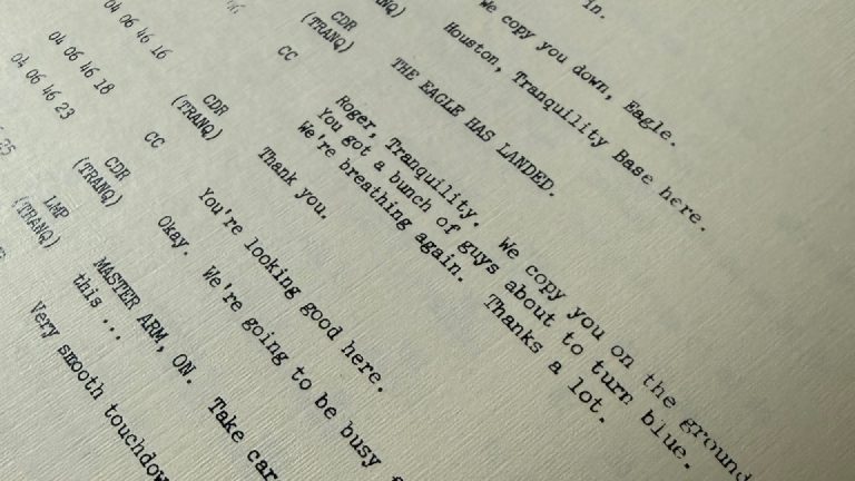 The slightly off-white paper and typewriter-style transcript, opened to the moment the Eagle lands.