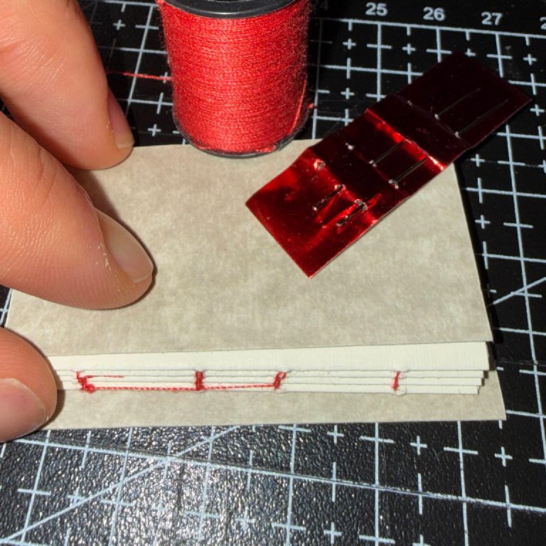 Sewing the signatures with red thread.